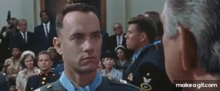 Animated GIF of Forrest Gump telling someone he was shot in the buttocks, with hand gestures.